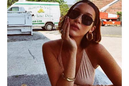 Bella Hadid genießt die Sonne in einem roséfarbenen Neckholder-Tanktop - Highlights ihres Outfits sind die schwarze Sonnenbr...