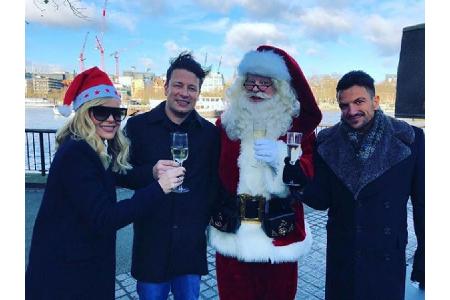 Sänger Peter André (re.) und Koch Jamie Oliver posieren mit Santa Claus und stoßen auf die vorweihnachtliche Zeit mit einem ...