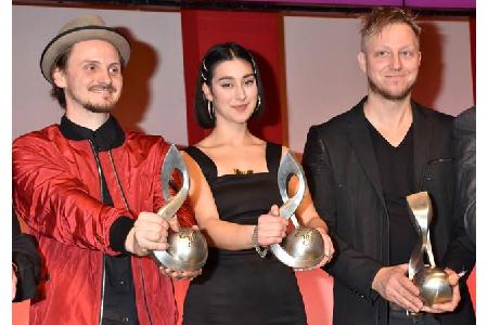 ...Maxim Richarz, Elif Demirezer und Martin Tingvall, die stolz ihre Trophäe in Form eines Notenschlüssels in die Kamera hie...