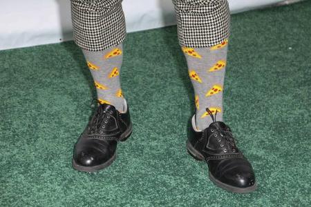 Es sind die Socken, die seinen Look so einzigartig skurril machen. Wobei Pizza und Golf als Kombination wohl eher selten sind.