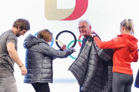 Bundespräsident Frank-Walter Steinmeier wird mit der offiziellen deutschen Olympia-Jacke ausgestattet.