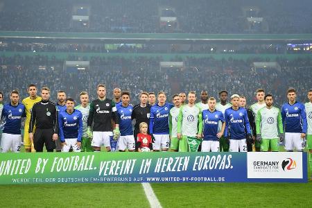 Vor dem letzten Viertelfinale zwischen Schalke 04 und dem VfL Wolfsburg posieren die beiden Mannschaften vor einem Banner, d...