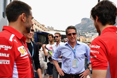 Schauspieler Hugh Grant lässt sich von zwei Ferrari-Verantwortlichen auf den neuesten Stand bringen.
