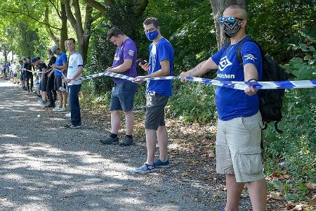 Um den Abstand zum Corona-Schutz einzuhalten, haben sich die Fans an einem blauweißen Absperrband rund um das Stadion aufges...