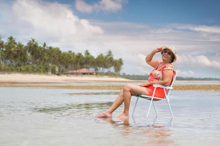 fröhliche Dame auf Campingstuhl im Meer in Kolumbien