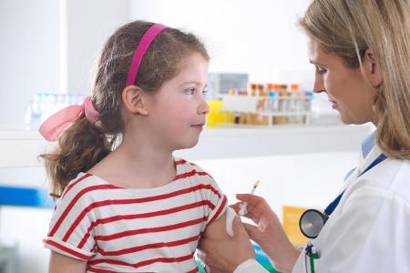 Female doctor giving a young girl a routine vaccination in t...