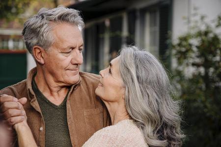 Affectionate senior couple in garden of their home in autumn...