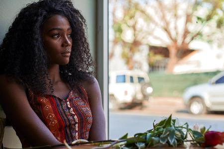 Portrait of young African woman with flowers on the table in...