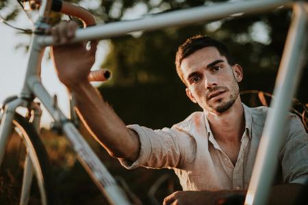 Portrait of a pensive young man with his bicycle outdoors mo...