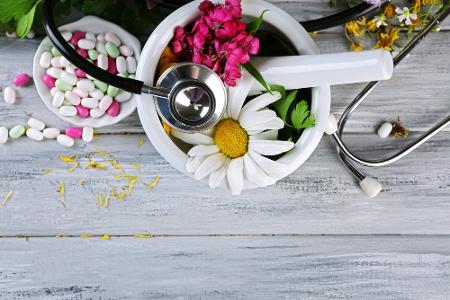 Pillen und medizinisches Gerät auf Blumen und Kräutern