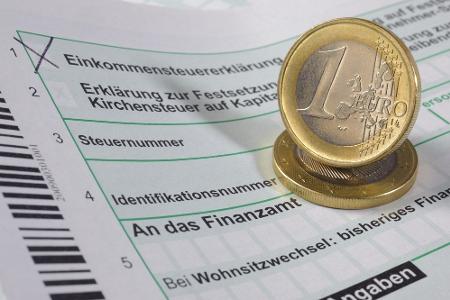 Formulare für die Steuererklärung und zwei Eurostücke