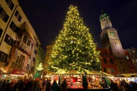 In der Altstadt von Innsbruck umrahmen mittelalterliche Häuser den Christkindlmarkt. Dabei darf eine große, mit Lichterkette...