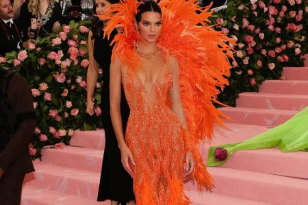 Kendall Jenner entschied sich für eine orangefarbene Robe mit Federoptik von Versace. Das enganliegende Kleid brachte ihre F...