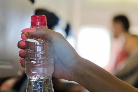 An Board viel Wasser trinken. Die Luftfeuchtigkeit im Flugzeug ist sehr niedrig, deshalb braucht der Körper umso mehr Wasser...