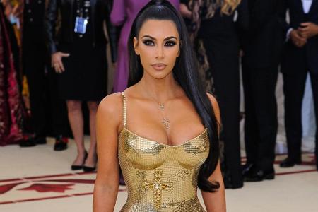 Ebenfalls im Metallic-Look erschien Kim Kardashian, die eine hautenge goldene Robe von Versace trug, die mit Kreuzen verzier...