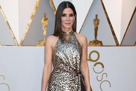 Sandra Bullock überzeugte auf dem roten Teppich in einem bodenlangen, gold-schwarzen Neckholder-Kleid von Louis Vuitton.