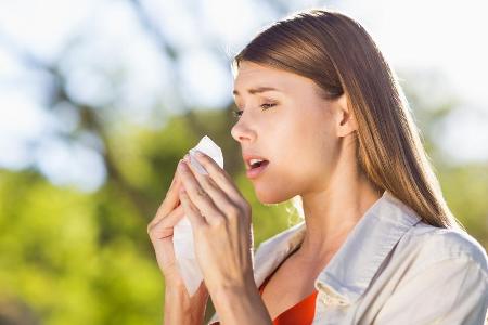 Niesen und Schnupfen sind typische Symptome bei einer Pollenallergie.