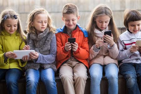 Typische Körperhaltung bei Erwachsenen und zunehmend auch Kindern: Kopf nach unten, Smartphone vorm Gesicht