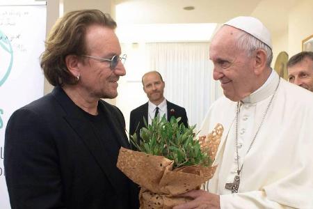 U2-Sänger Bono (l.) überreicht Papst Franziskus ein Pflänzchen zur Begrüßung