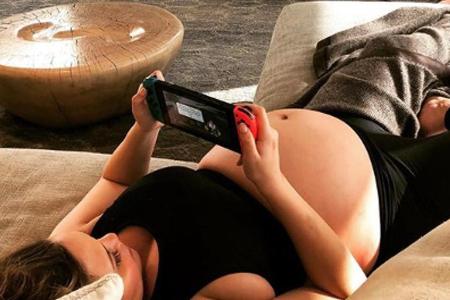 Chrissy Teigen mit Baby-Bauch auf dem Sofa Chrissy Teigen mit Baby-Bauch auf dem Sofa