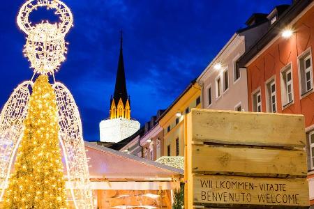 Adventmarkt in Villach mit der Kirche als Riesenkerze