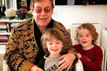 Elton John bestaunt seine Geburtstagstorte zusammen mit seinen Söhnen Elijah und Zachary