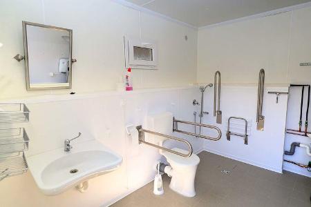 Behindertengergerechtes Badezimmer mit Waschbecken, Dusche und Toilette