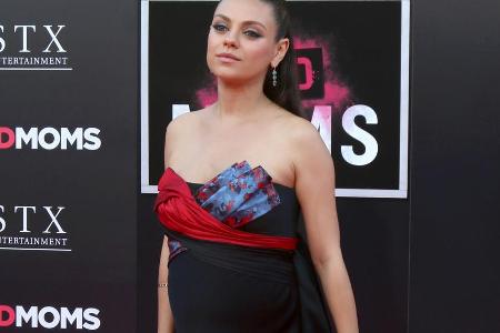 Die Fotowand tarnt, doch bei genauem Hinsehen erkennt man den wachsenden Baby-Bauch von Mila Kunis