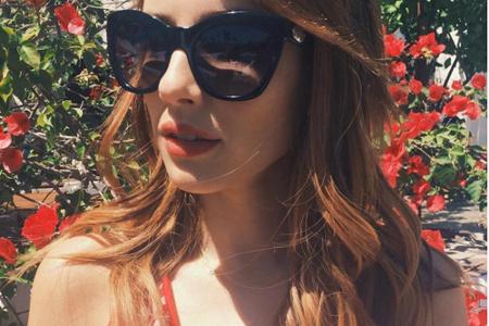 Bei diesem Coachella-Look kommt Sixties-Feeling auf: Emma Roberts mit großer Sonnenbrille, gewellten Haaren und süßem rot-we...