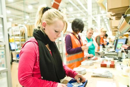 Eine Amazon-Mitarbeiterin im Logistikzentrum verpackt ein Geschenk Eine Amazon-Mitarbeiterin im Logistikzentrum verpackt ein Geschenk