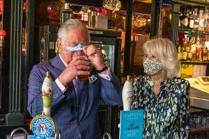 Prinz Charles lüftet die Maske für einen Schluck Bier
