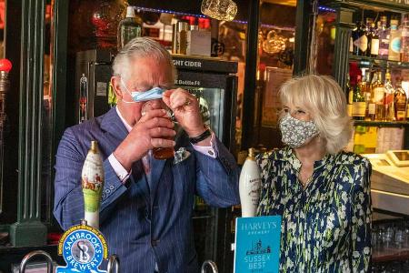 Prinz Charles genießt ein Bier, Ehefrau Camilla freut sich mit ihm.