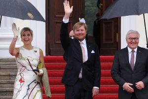 Máxima und Willem-Alexander grüßen in Berlin unterm Regenschirm