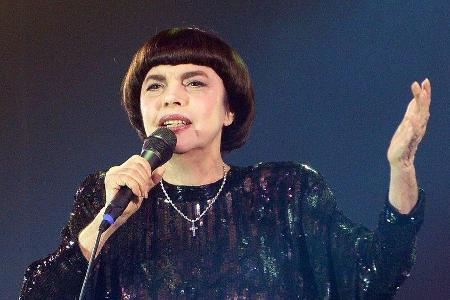 Schwarzes Kleid, Pagenfrisur, erhobene Hand: Mireille Mathieu steht noch auf der Bühne wie vor 50 Jahren.