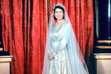 Elizabeth trägt an ihrem großen Tag ein Satin-Hochzeitskleid mit langem Schleier, designt von Norman Hartnell.