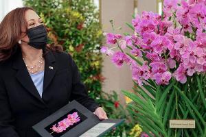 Kamala Harris steht neben einem Exemplar der nach ihr benannten Orchidee "Papilionanda Kamala Harris".