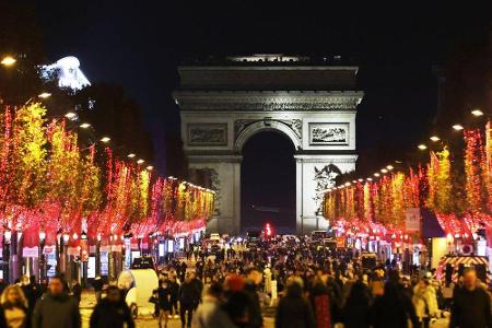 Paris erstrahlt in Rot: Die Prachtstraße Avenue des Champs-Élysées führt mit erleuchteten Bäumen direkt auf den Arc de Triom...