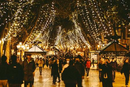 In Barcelona ist die beliebte Promenade La Rambla hell erleuchtet. In den Bäumen, die die Straße säumen, sind zahlreiche Lic...