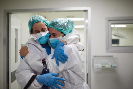 Zwei Krankenhausmitarbeiter umarmen sich in Schutzkleidung