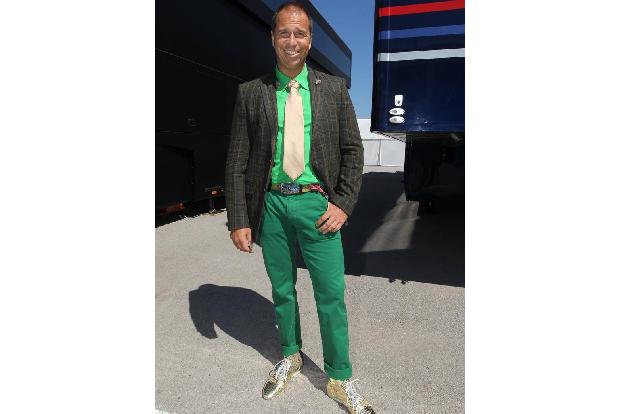 Goldene Schuhe, goldene Krawatte, knallbunter Gürtel, hellgrünes Hemd, dunkelgrüne Hose und ein farblich schwer definierbare...