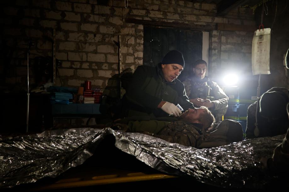 Ein Mann gibt einem verwundeten ukrainischen Soldaten in einem Unterstand in Donezk etwas zu trinken.