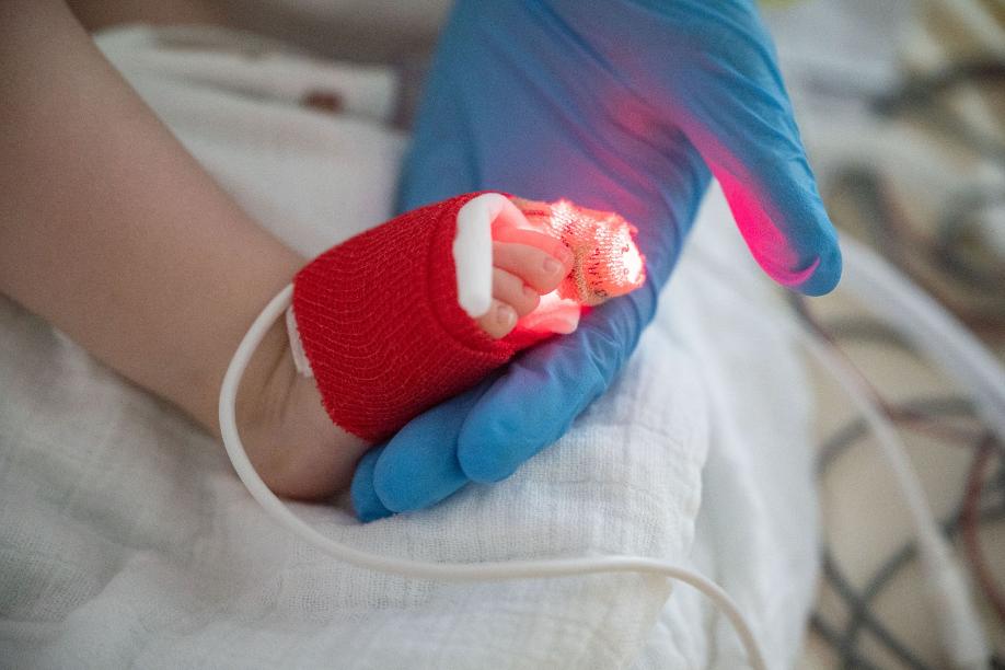 Eine Intensivpflegerin hält auf einer Kinder-Intensivstation in Stuttgart den Fuß eines jungen Patienten in der Hand.