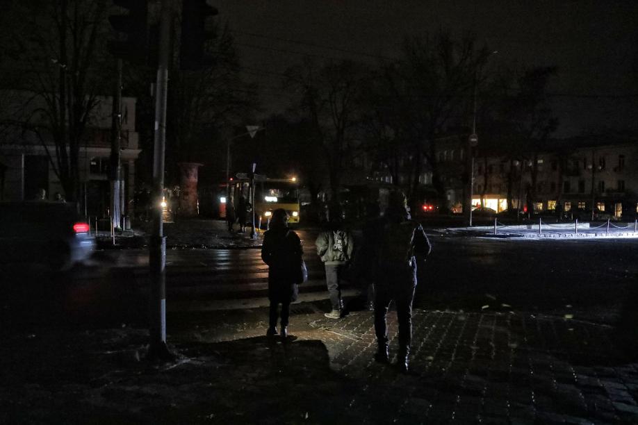 Fußgänger halten sich in Odessa an einer Kreuzung auf einer dunklen Straße auf, da die Stadt von Stromausfällen betroffen ist.