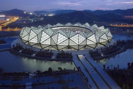 Made in China - Das Longgang Stadium liegt auf einem künstlich angelegten Gewässer und zieht die Blicke mit der würfelförmigen Fassade auf sich.