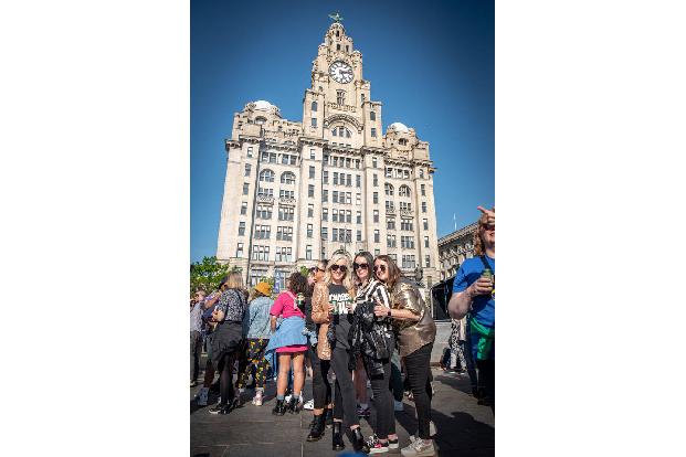 Hier posieren Besucher*innen vor dem legendären Liver Building, einem der Wahrzeichen der Stadt, die die Skyline von Liverpool bilden.