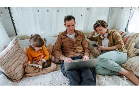 Father, mother and little daughter with gadgets sitting in the camper