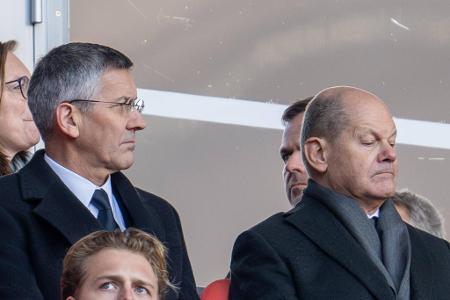Bundeskanzler Olaf Scholz (r.) sitzt auf der Tribüne neben Bayern-Präsident Herbert Hainer.