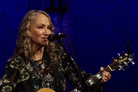 Frau mit Gitarre hinter Mikrofon
