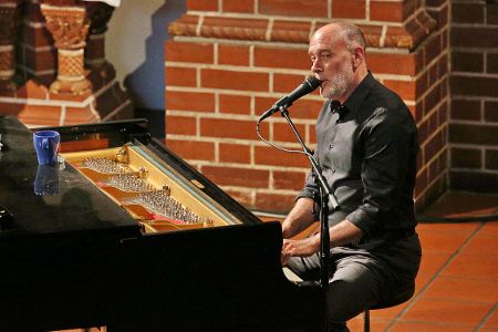 Mann am Klavier singt ins Mikrofon