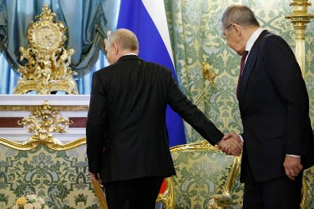 Der russische Präsident Wladimir Putin (l) gibt dem russischen Außenminister Sergej Lawrow die Hand, als dieser zu einem Treffen mit dem kubanischen Präsidenten Diaz-Canel im Großen Kremlpalast eintrifft.